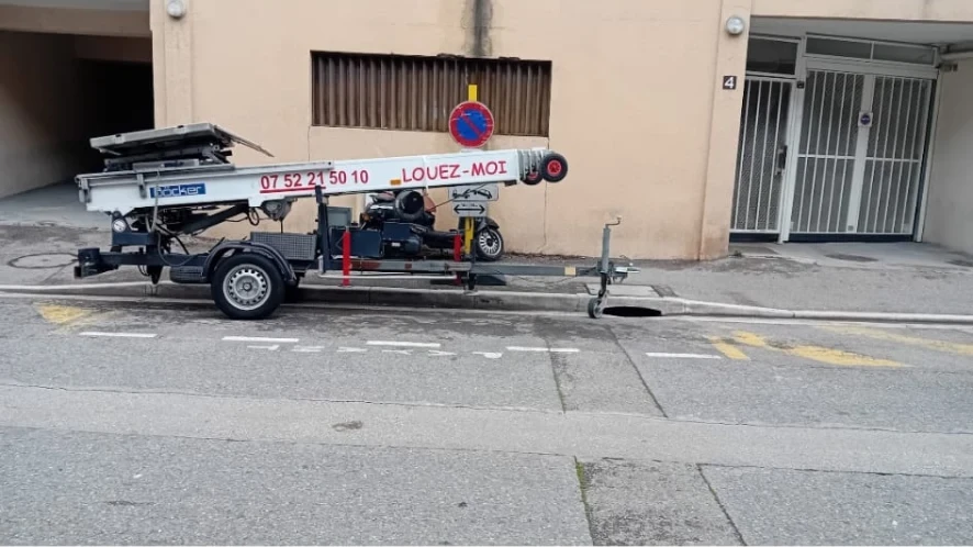Monte-meubles replié sur une remorque stationnée devant un immeuble
