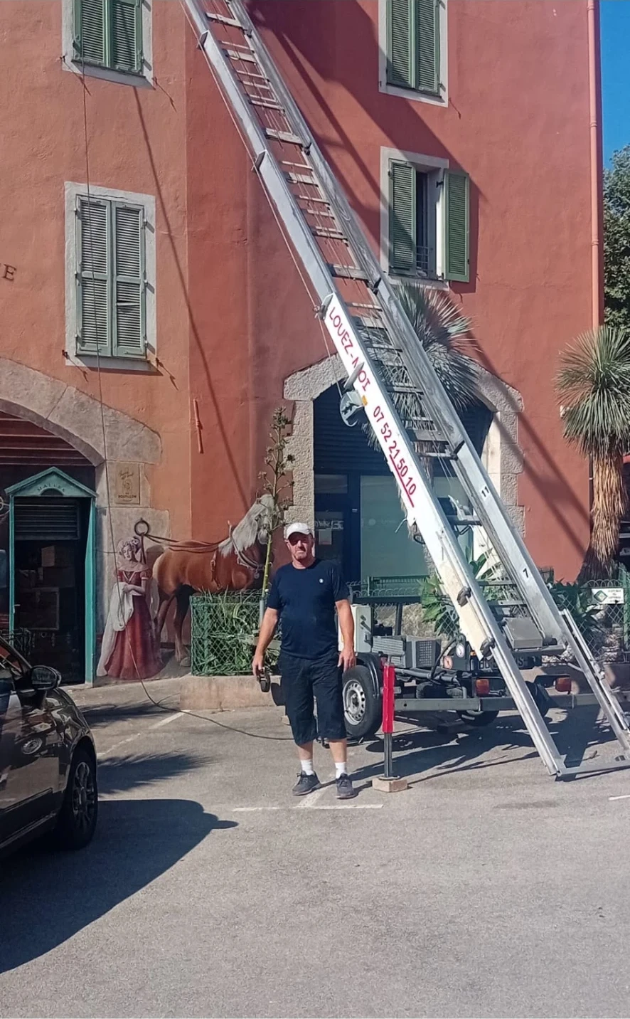 Personne devant une façade ocre, à côté d’un monte-meubles déployé